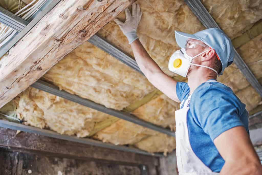 Man inspects installed insulation at home | Attic Insulation & Air Sealing by First Defense Insulation